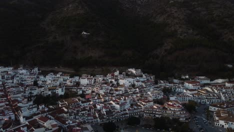 Beautiful-white-city-near-massive-mountain,-aerial-drone-view