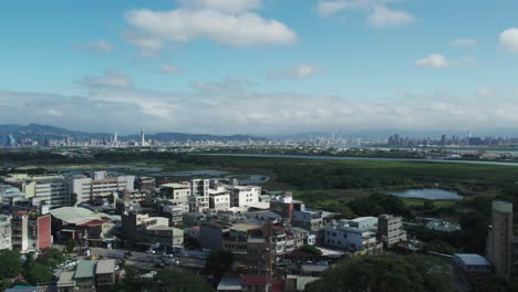 Lush-Guandu-Wetland-with-Taipei-Cityscape-in-Distance,-Aerial