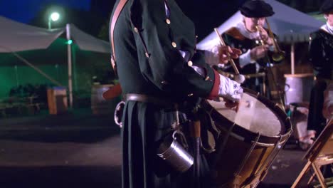 man-in-historic-uniform-playing-drums-in-military-orchestra-at-night-time