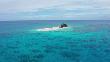 Aerial-View-of-Small-Coral-Island-and-Turquoise-Ocean-Water