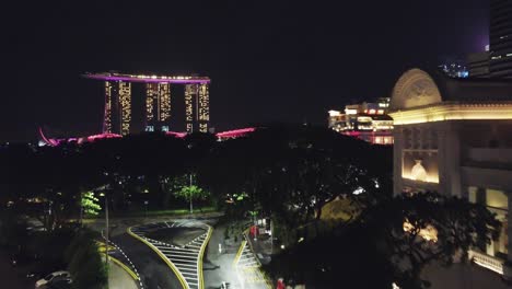 Drone-shot-past-trees-and-almost-empty-street-towards-Marina-bay-sands-Singpore