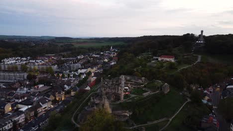 Castle-ruins-on-hilltop-surrounded-by-township-of-Valkenburg,-aerial-view