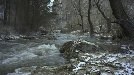 Swirling-streams-of-a-mountain-river-which-passes-between-high-rocks-with-deciduous-and-fir-forests-in-winter