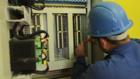 Male-electrician-carefully-uses-screw-driver-in-electrical-panel-at-factory