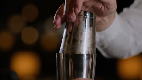 Closeup-shot-of-a-bartender-closing-up-a-cocktail-shaker-and-beginning-to-shake-cocktail