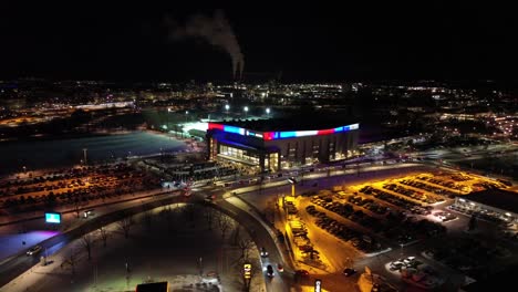 Aerial---Circulating-around-Saab-Arena-in-Linköping,-Sweden-before-LHC-hockey-match---People-entering-and-queueing---Winter-night