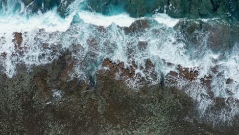 Top-Down-Aerial-View-of-Ocean-Waves-Splashing-Coral-Reef-Near-Tropical-Island