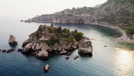 Drohne-Kreist-Bei-Sonnenuntergang-Um-Die-Insel-Isola-Bella-In-Der-Nähe-Der-Küste-Von-Taormina