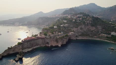 Toma-Aérea-Sobre-El-Océano-Mientras-Un-Dron-Orbita-Alrededor-De-Una-Isla-Al-Atardecer-Cerca-De-Taormina,-Sicilia