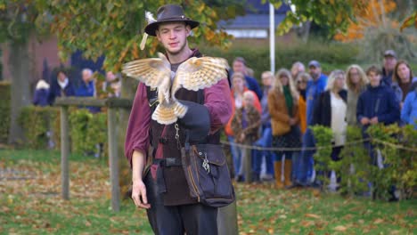 Owl-flies-from-falconers-hand-to-other-man-at-bird-show-while-crowd-is-looking