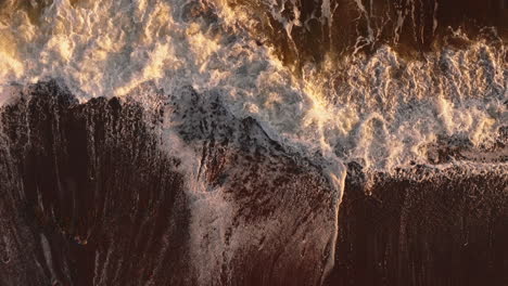 Slow-motion-descending-aerial-view-of-ocean-waves-at-magic-hour