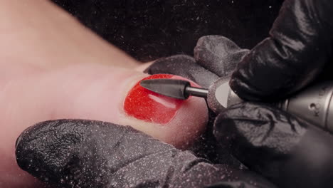 Bright-red-nail-polish-getting-removed-of-a-toe-during-pedicure-in-slow-motion-with-all-the-gel-flying-off