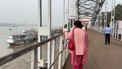 Rear-view-of-an-Indian-girl-looking-at-the-ferry-boat-from-the-bridge-over-river-Hooghly-in-Kolkata,-India
