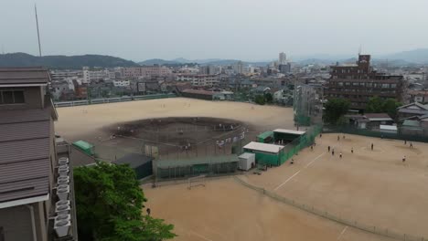 Panoramic-aerial-drone-fly-above-sports-baseball-soccer-field-at-Japanese-school