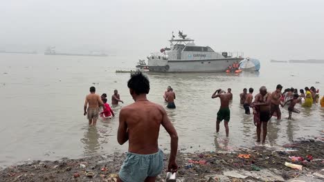 Wide-shot-of-Hindus-taking-bath-at-Babu-ghat-for-the-celebration-of-Sankranti-festival-with-ferries-at-background-in-Kolkata