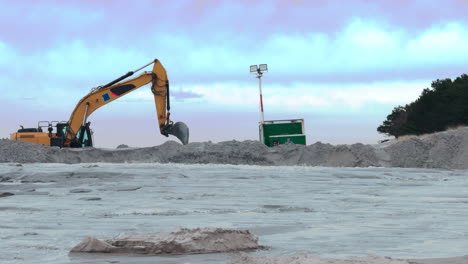 A-large-excavator-shovels-sand-that-has-been-washed-up-from-the-Baltic-Sea-to-repair-the-beach