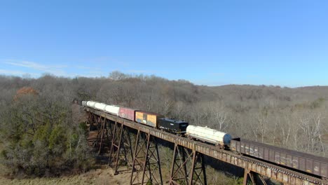 Aerial-Shot-Pulling-Back-from-a-Mixed-Freight-Train-Crossing-the-Pope-Lick-Trestle-in-Louisville,-Kentucky-on-a-Sunny-Winter-Day