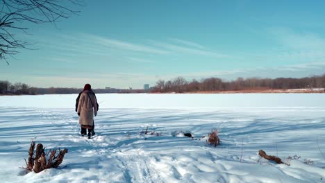Man-and-woman-couple-walking-go-away-on-vast-snow-carpet-in-winter-long-shot