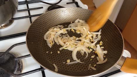 Julienne-onion-is-sauteed-and-stirred-with-a-wooden-spoon,-home-cooking