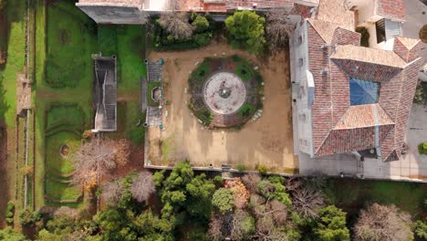 Top-down-aerial-view-of-french-chateau-building-and-scenic-forest-garden-in-Jacou,-France