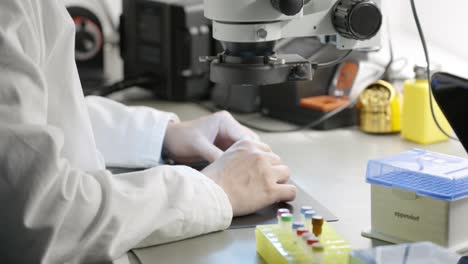 Male-Scientist-in-white-lab-coat-looking-at-sample-using-microscope