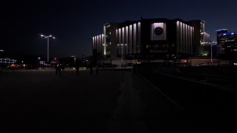 Night-footage-of-The-National-Palace-of-Culture---Congress-Centre-Sofia-,-with-people-walking-around