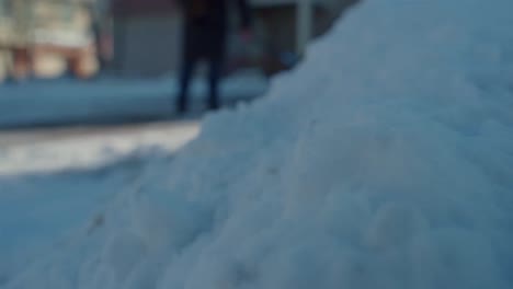Close-up-accumulated-snow-with-woman-shoveling-in-front-of-house-in-winter-slow-motion-low-shot