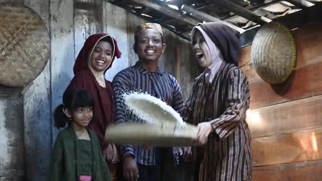 A-happy-Javanese-family-with-their-two-children-with-a-tray-of-rice,-Central-Java,-Indonesia_slow-motion