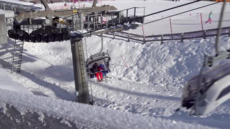 Two-people-ride-a-chairlift-in-a-ski-resort-in-South-Tyrol,-Italy