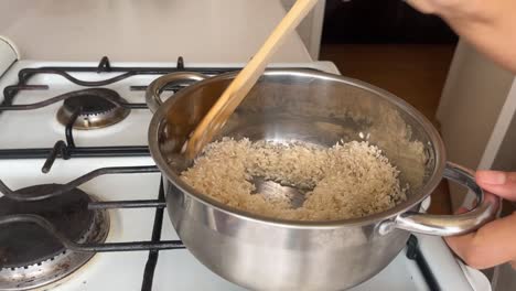 Zubereitung-Von-Reis,-Er-Wird-In-Einem-Stahltopf-Gebraten,-Der-Koch-Rührt-Ihn-Mit-Einem-Holzlöffel-Um