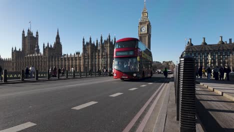Black-Taxis-And-Red-Double-Decker-Bus-Driving-Over-Westminster-Bridge-With-Big-Ben-In-Background-On-Sunny-January-Day