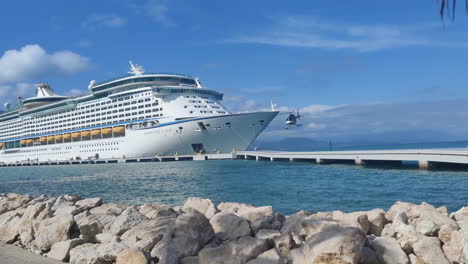 Witness-the-thrill:-helicopter-takes-off-from-pier-adjacent-to-massive-cruise-ship,-adding-an-exhilarating-touch-to-the-Caribbean-island-experience