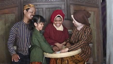 A-happy-Javanese-family-with-their-two-children-with-a-tray-of-rice,-Central-Java,-Indonesia