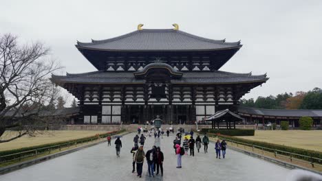 Visitors-at-the-Todai-ji-Temple,-a-historical-building-in-Nara,-Japan-with-tourists-walking-and-sightseeing,-cloudy-day