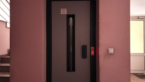 waiting-for-the-elevator-to-arrive-on-the-ground-floor-of-an-apartment-building-with-pink-walls