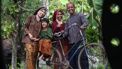 A-happy-Javanese-family-with-their-two-children-on-an-ancient-bicycle,-Central-Java,-Indonesia