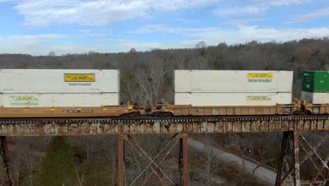 Aerial-Side-Shot-of-an-Intermodal-Freight-Train-Crossing-the-Pope-Lick-Trestle-in-Louisville,-Kentucky-during-the-Winter