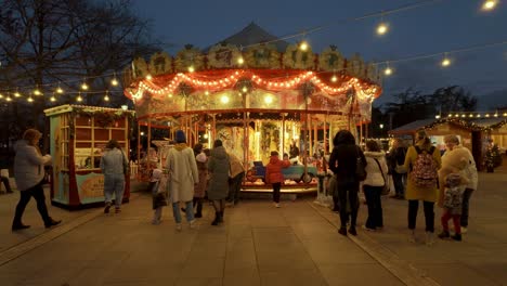 Parents-standing-in-front-of-a-carousel-as-their-kids-get-on-it,-at-the-Sofia-Christmas-Fest-2023