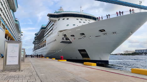 Amid-the-pier's-hustle,-determined-group-of-individuals-pulls-hefty-mooring-line,-securing-massive-cruise-ship-with-teamwork-and-precision-|-Group-of-people-pulling-heavy-mooring-line-of-Ship