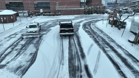 Pickup-trucks-with-snow-plows-clearing-snow-in-parking-lot