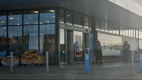 Shoppers-entering-ALDI-brand-supermarket-buying-cheap-food-groceries
