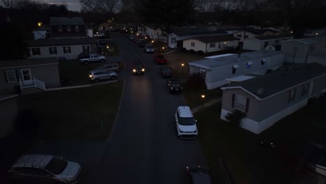 Car-headlights-at-night-during-through-American-residential-trailer-park-mobile-home-neighborhood-in-evening-darkness