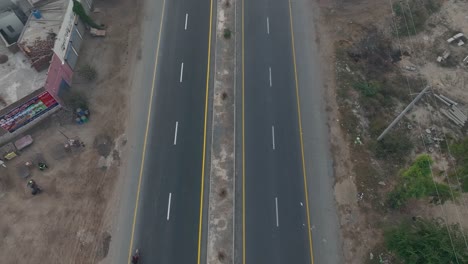 Rückwärtsaufnahme-Einer-Autobahn-Mit-Vorbeifahrenden-Fahrzeugen-Und-Einer-Industrie-Daneben-In-Punjab,-Pakistan