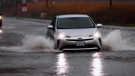 Toyota-Car-driving-and-splashing-on-flooded-Street-during-heavy-rain-in-america,-tracking-shot