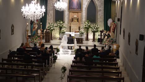 Hochzeitszeremonie-In-Einer-Kleinen-Katholischen-Kirche,-Junges-Lateinamerikanisches-Paar-Sitzt-Am-Altar