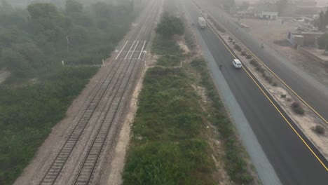 Aerial-view-of-Sahiwal-to-Multan-Road-with-vehicle-passing-by-during-foggy-evening-in-Punjab,-Pakistan