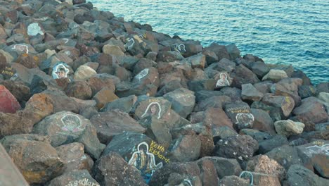 Sea-wall-supporting-rocks-painted-with-picture-outlines-and-names-of-famous-people