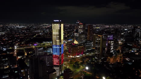 Luftaufnahme-Umkreisende-Beleuchtete-Wolkenkratzer-In-Der-Innenstadt-Von-Bogota,-Nacht-In-Kolumbien