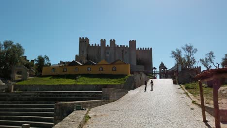 Inner-park-of-the-Óbidos-Castle,-cobblestone-leads-to-the-historical-fortress-and-church-tower-in-Portugal