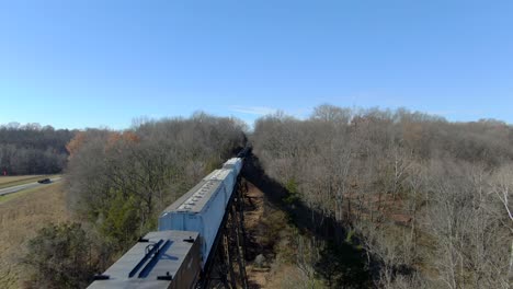 Aerial-Shot-Orbiting-Over-a-Mixed-Freight-Train-Crossing-the-Pope-Lick-Trestle-in-Louisville,-Kentucky-on-a-Sunny-Winter-Day